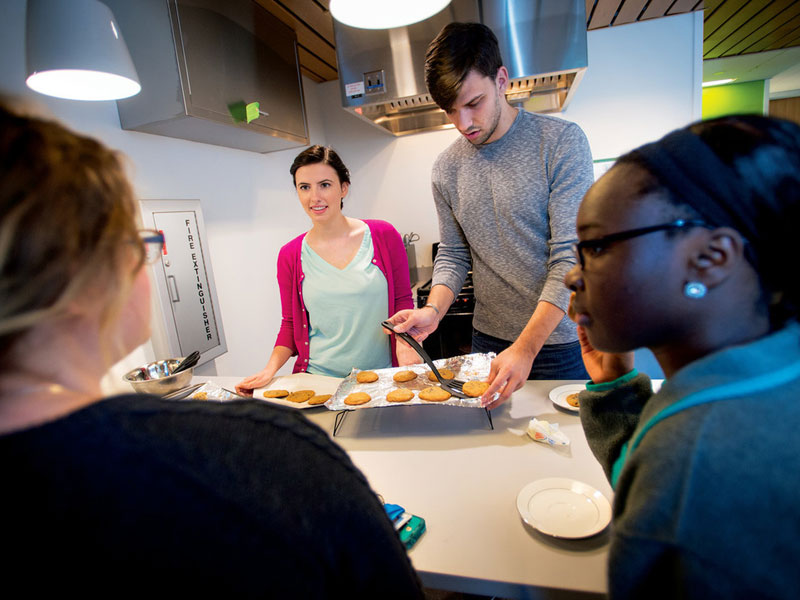 Four students talk while preparing a meal