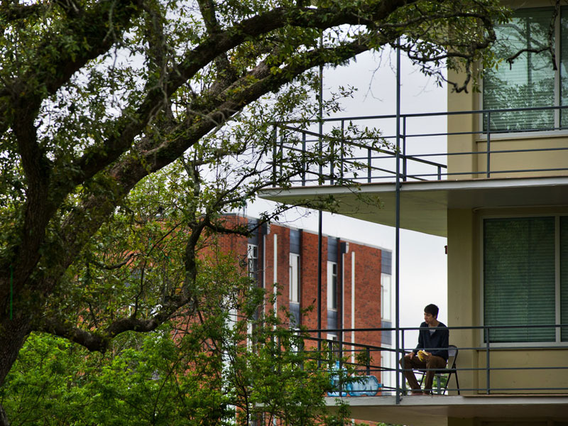 Student sits on balcony of residence hall