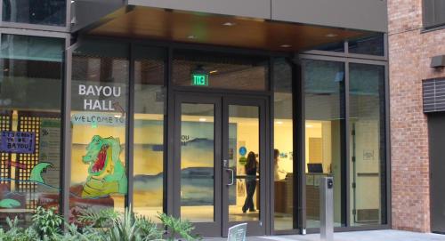 Bayou Hall entrance features 'WELCOME TO' text, a green alligator mural, and 'IT'S GREAT TO BE BAYOU!' signage.
