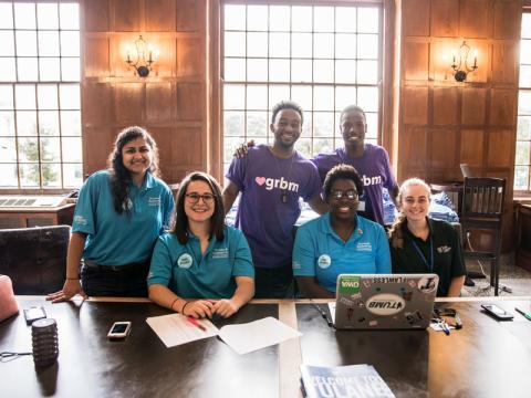 Six students pose for camera at desk