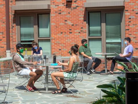 Students chat at outdoor tables on campus
