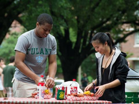Two students peel crawfish on the quad